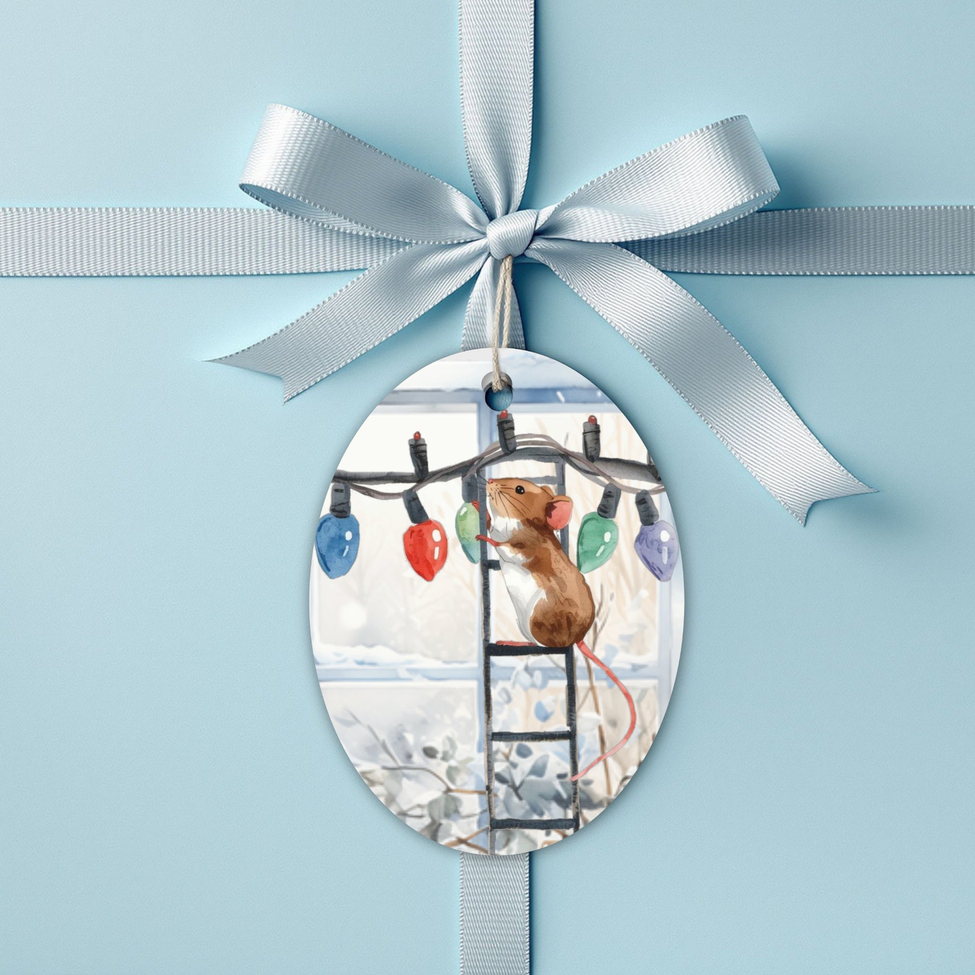 Decorative christmas gift tag with a mouse and Christmas lights, tied with a white ribbon on a light blue present.
